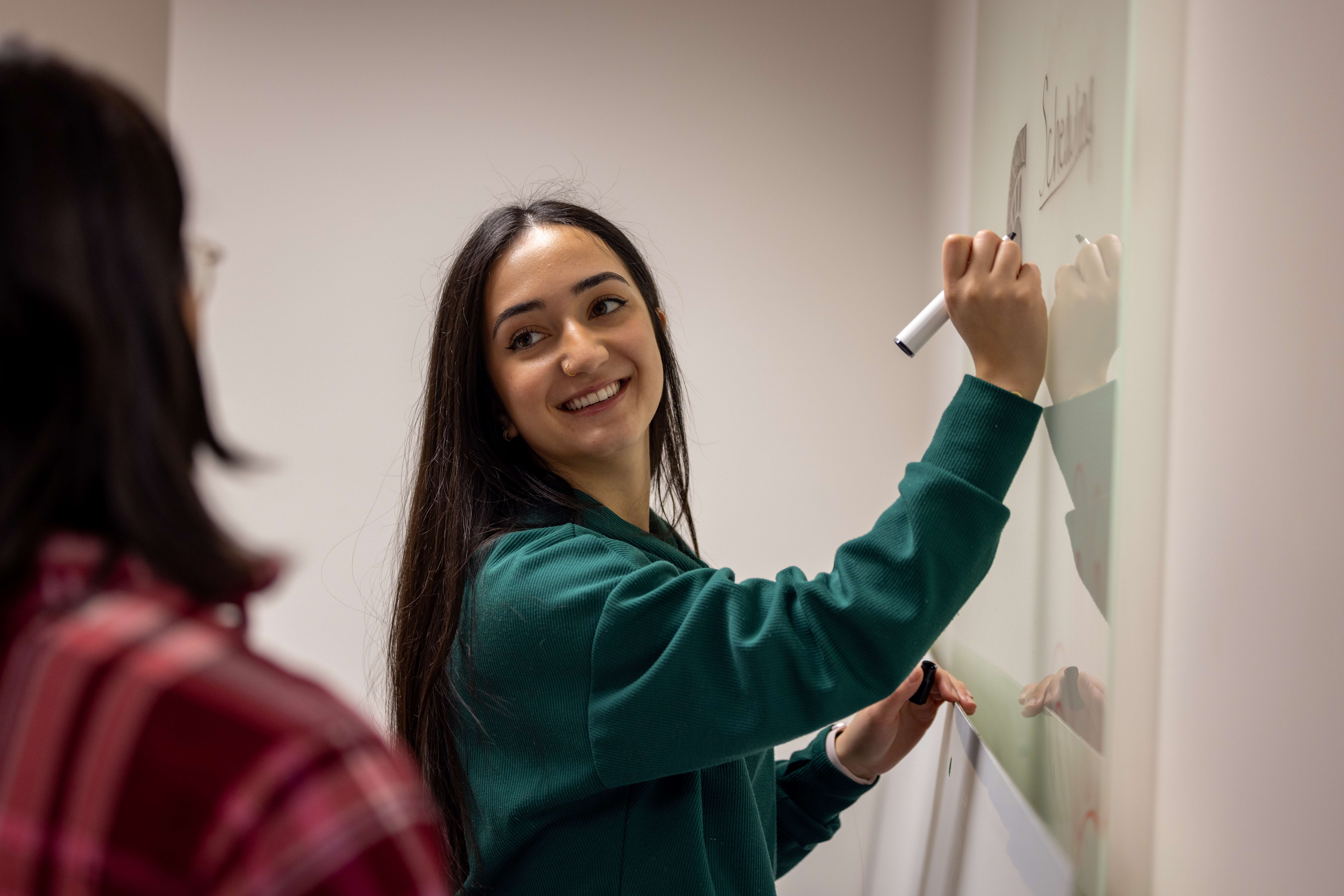 A photo of Saara Ashtiani writing on a whiteboard