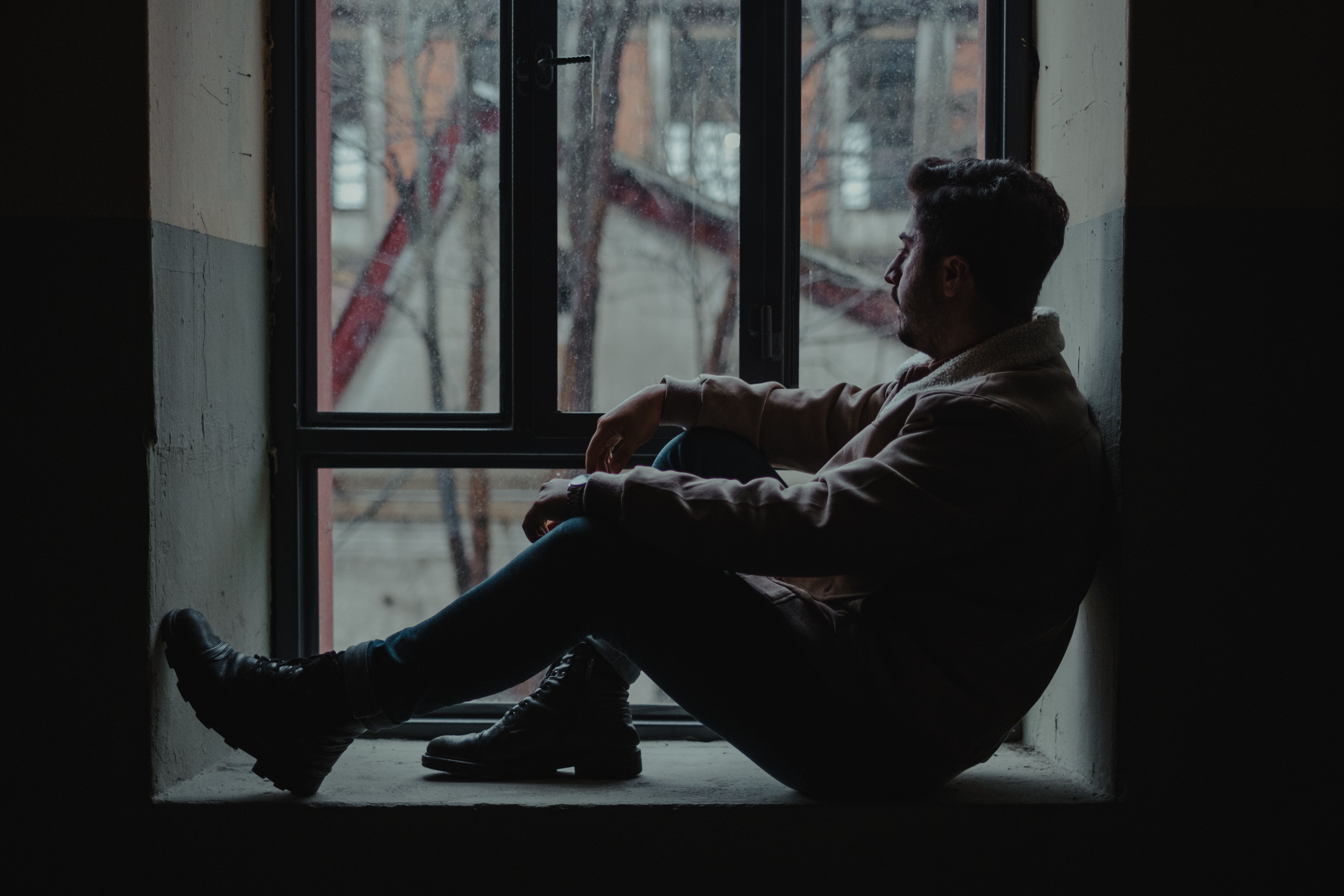 A man sitting down and staring out of a window.