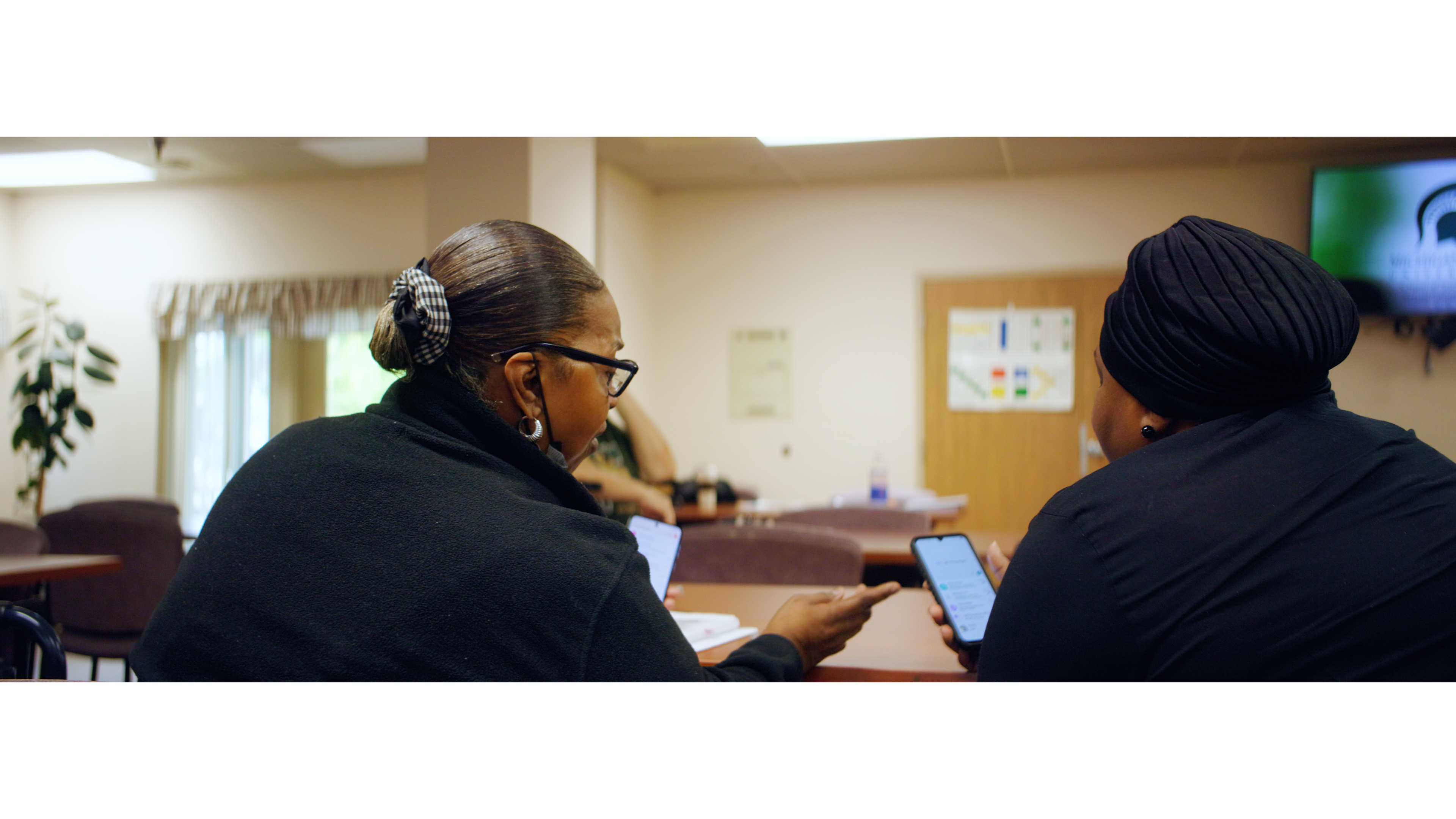 Two women helping each other learn about digital literacy