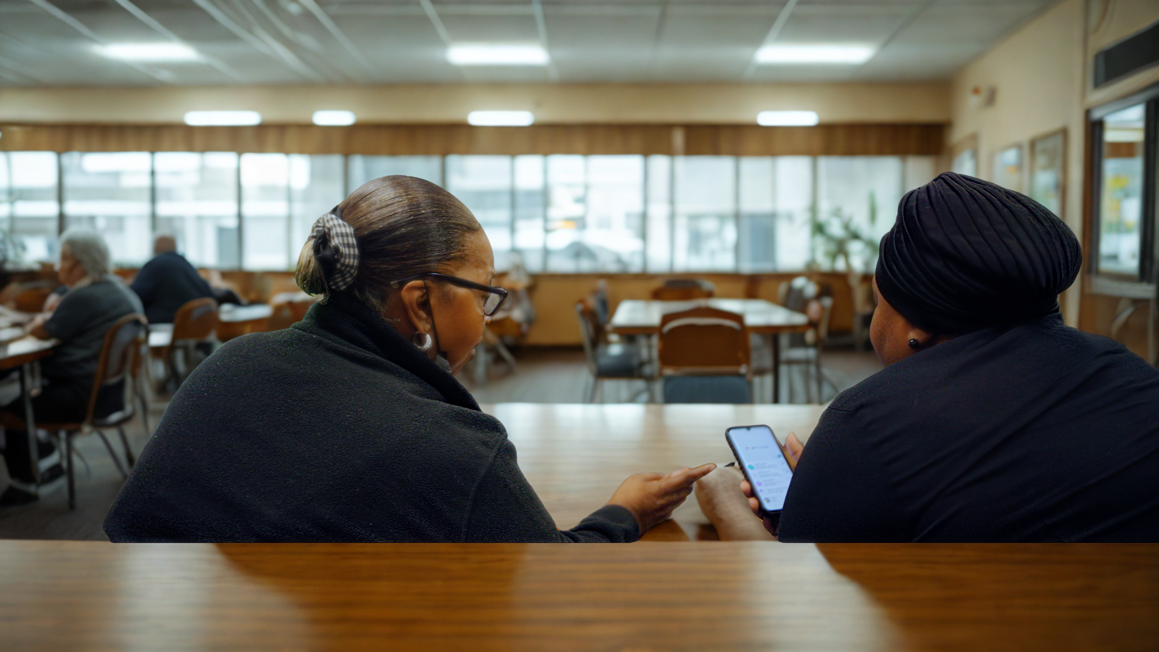 Two women showing each other apps on a phone